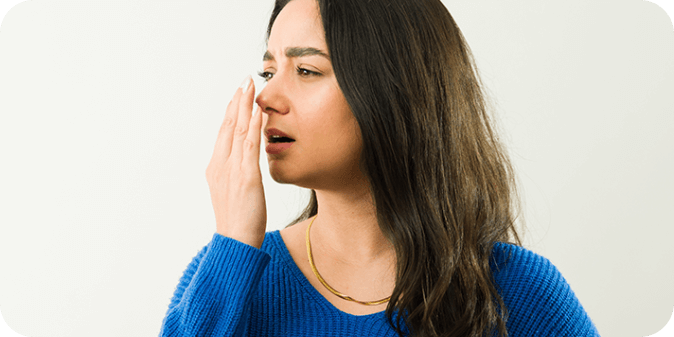 A lady frowning and breathing out with her hand in front of her face. 
