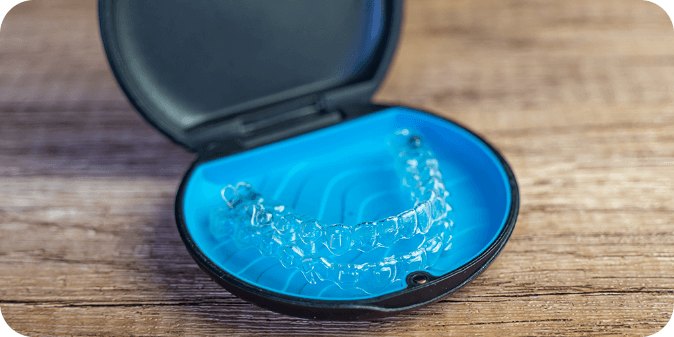 A pair of Invisalign aligners in a blue Invisalign case.